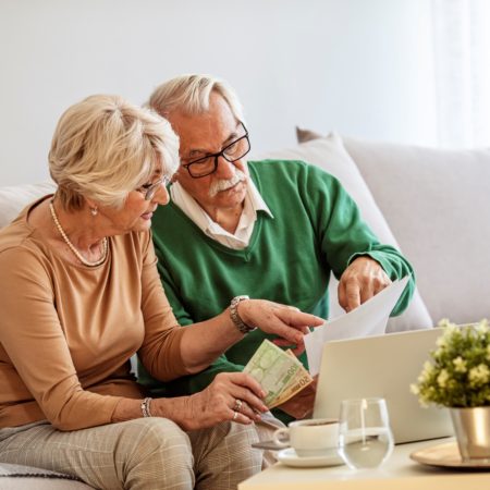 A senior couple working on their bills using a laptop.