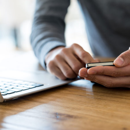Man holding cell phone and laptop